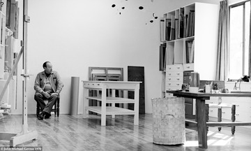 Gunther Gerzso sitting in his studio around 1970 in his typical work clothes. Photo by J. Michael Gerzso. The studio had a wooden floor, 12ft ceiling and white walls. On the left and right walls are painting storage shelves. In the center a work table for stretching canvases and framing, and to the right is his desk where he designed all his works.