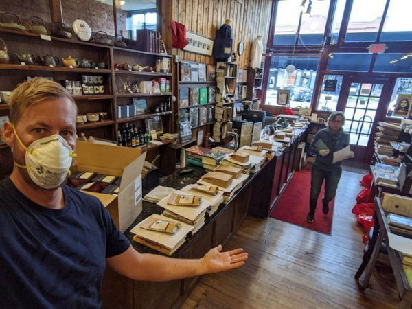 Inside view of Trident Booksellers book area looking out toward Pearl Street. To the left is the cafe (not seen).
In this photograph, an employee is showing tables with products they sell for a special occasion.