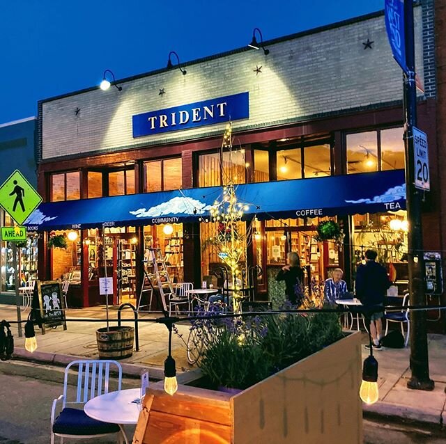 Vista exterior de la librería Trident Booksellers al atardecer con el cielo sin nubes y de azul oscuro.
El toldo tiene nieve de una tormenta de dias anteriores. La calle está cerrada a circulación automobiles.